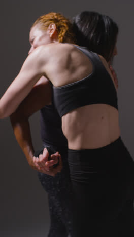 Vertical-Video-Studio-Shot-Of-Two-Mature-Women-Wearing-Gym-Fitness-Clothing-Doing-Cardio-Exercise-Running-On-The-Spot-Together-1